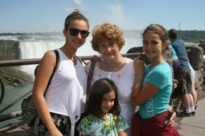 Three young girls and grandmother photographed in front of Niagra Falls