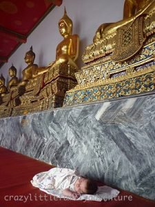Golden statues of Buddha looking over a sleeping baby