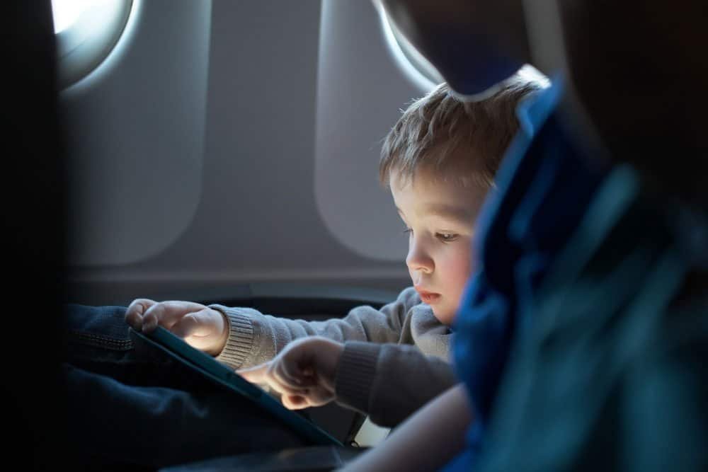 Little boy on a plane engrossed in an ipad